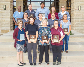 13 staff members pose with their staff awards in the VBEC courtyard