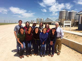 Dr. Griffin and several students pose in front of a farm with silos in the background