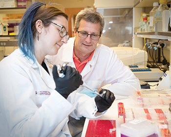 a male researcher mentors a female trainee while pipetting a sample